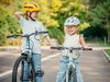 Due bambine sorridenti cercano di mantenere l’equilibrio in sella alla bici