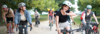[Translate to Italian:] Junge Lehrer:innen auf dem Velo. Eine Frau winkt freundlich in die Kamera.