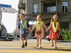 Tre bambini dell’asilo attraversano mano nella mano le strisce pedonali